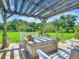 Relaxing pergola-covered patio with wooden table and white benches at 4 Casarena Ct, Winter Haven, FL 33881