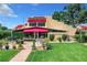 Back exterior view of two-story home with red awnings and lush landscaping at 4 Casarena Ct, Winter Haven, FL 33881