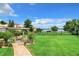 Large grassy backyard with a brick pathway, pergola, and lake view at 4 Casarena Ct, Winter Haven, FL 33881