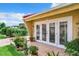 Backyard patio with white french doors, landscaping, and a pergola in the background at 4 Casarena Ct, Winter Haven, FL 33881