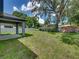 Large backyard with mature trees and a covered patio at 213 Cordova Rd, Auburndale, FL 33823