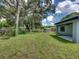 Spacious backyard with mature trees and a home with covered patio at 213 Cordova Rd, Auburndale, FL 33823