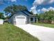 Front view of a newly built house with a gray exterior, white garage door, and landscaping at 213 Cordova Rd, Auburndale, FL 33823