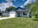 New house with gray exterior, white garage door, and nicely manicured lawn at 213 Cordova Rd, Auburndale, FL 33823