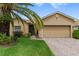 Tan house with a palm tree, brick driveway and two car garage at 4432 Waterford Dr, Lake Wales, FL 33859