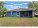 Exterior view of the home with blue siding, screened porch, and grassy backyard at 329 Lake Vista Dr, Auburndale, FL 33823