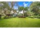 Spacious backyard with lush lawn, tropical plants, and a view of the house at 2931 Chickasaw Cir, Haines City, FL 33844