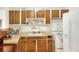 Galley kitchen with wood cabinets, white appliances, and tiled backsplash at 512 N 4Th St, Haines City, FL 33844