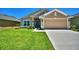 Tan house with a two-car garage, landscaping, and a well-maintained lawn at 507 Tanaro Ln, Haines City, FL 33844