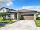 One-story house with a brown garage door, landscaping and palm trees at 278 Alford Dr, Davenport, FL 33896