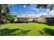 Spacious backyard with lush grass and view of home's back at 708 Canberra Rd, Winter Haven, FL 33884