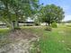 Large backyard with mature trees, partial grass, and a swing set at 126 Bermuda Ct, Winter Haven, FL 33880