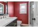 Bathroom with red walls, white vanity, and glass shower at 1324 Mirror Nw Ter, Winter Haven, FL 33881