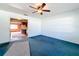 Living room with blue carpet, ceiling fan, and view into kitchen at 221 Dorothy St, Auburndale, FL 33823