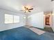 Living room featuring blue carpet, ceiling fan and access to hallway at 221 Dorothy St, Auburndale, FL 33823