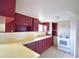 A galley kitchen with white appliances and dark red cabinets at 738 Strain Blvd, Lakeland, FL 33815