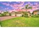 Beautiful villa with 3-car garage, lush landscaping, and a brick driveway, showcasing a stunning sunset at 1644 Linz Ct, Winter Haven, FL 33884