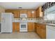 Kitchen with light wood cabinets, white appliances, and tile flooring at 3309 Raleigh Dr, Winter Haven, FL 33884