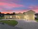 Evening view of a charming yellow house with a large driveway and three-car garage at 3604 Blackmoor Ln, Lake Wales, FL 33859