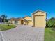 Front view of a charming yellow house with a large driveway and three-car garage at 3604 Blackmoor Ln, Lake Wales, FL 33859