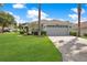 Single-story home with gray garage door, lush lawn, and palm trees at 1591 Forest Hills Ln, Haines City, FL 33844