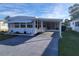 White mobile home with carport and screened patio, nestled in a grassy yard at 161 Bonnie Dr, Auburndale, FL 33823