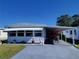 White mobile home with carport, landscaping, and boat in driveway at 161 Bonnie Dr, Auburndale, FL 33823