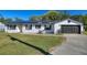 White brick ranch house with solar panels, attached garage, and landscaped lawn at 1610 Meadow Ne Ln, Winter Haven, FL 33881