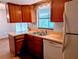 Compact kitchen featuring wood cabinets, double sink, and white appliances at 16 Kendra Ct # 16, Winter Haven, FL 33880