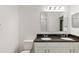 Bright bathroom featuring white cabinets, double sinks, and a dark granite countertop at 209 Flatwoods Loop, Davenport, FL 33837