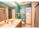 Bathroom with teal walls, single vanity, and access to the shower and backyard at 218 College Grove Ne Cir, Winter Haven, FL 33881