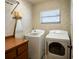 Laundry room with white washer and dryer units and wood cabinetry at 218 College Grove Ne Cir, Winter Haven, FL 33881