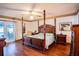 Main bedroom with four-poster bed, wood floors, and access to a patio at 218 College Grove Ne Cir, Winter Haven, FL 33881