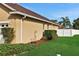 Landscaped side yard with tan house exterior, lush greenery, and white fence at 231 Terranova Blvd, Winter Haven, FL 33884