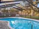 Sparkling blue pool with a screened enclosure and wooden bench at 4210 Old Colony Rd, Mulberry, FL 33860