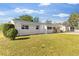 Exterior view of a renovated ranch-style home with a gray roof and a spacious yard at 80 Garrison Ln, Frostproof, FL 33843