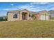 Tan house with solar panels, a two-car garage, and a grassy yard at 117 Dinner Lake Ave, Lake Wales, FL 33859