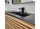 Close-up of a modern bathroom vanity with a black sink and waterfall faucet at 210 W Illiana St, Orlando, FL 32806