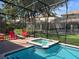Screened pool and spa with red lounge chairs at 1402 Wexford Way, Davenport, FL 33896