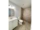 Clean bathroom with white vanity, tile shower, and stone flooring at 9115 Se 88Th St, Ocala, FL 34472