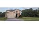 Two-story home with gray siding, brick accents and a three car garage at 3937 Reed Grass Pl, Kissimmee, FL 34746