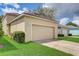 House exterior showcasing a beige two-car garage with a well-manicured lawn at 6943 Cupseed Ln, Harmony, FL 34773