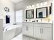 Double vanity bathroom with white cabinets and marble floors at 107 Julliard Blvd, Davenport, FL 33897