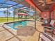 Relaxing pool area with screened enclosure, lake view, patio furniture, and red umbrella at 955 Mansfield Rd, Tavares, FL 32778