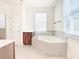 Bathroom with corner soaking tub, wood cabinets, and tile flooring at 1134 Tapestry Dr, Celebration, FL 34747
