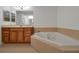 Bathroom with corner bathtub, wood cabinets, and tiled flooring at 10233 Serotina Ct, Orlando, FL 32832