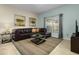 Living room with a leather sectional sofa, coffee table, and window at 4825 Clock Tower Dr, Kissimmee, FL 34746