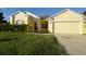 Yellow house with two-car garage and landscaped yard at 2221 The Oaks Blvd, Kissimmee, FL 34746