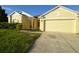 Yellow house with two-car garage and landscaped yard at 2221 The Oaks Blvd, Kissimmee, FL 34746