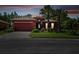 Red two-story house with paved driveway and landscaping at dusk at 806 Ebb Tide Ln, Poinciana, FL 34759